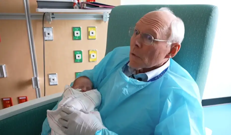 man cuddles babies NICU